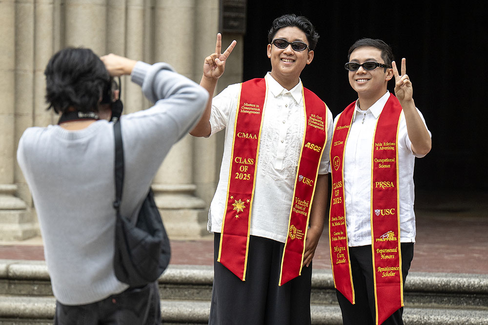 Kyle Revale, left and Miguel Bernas, right, pose for a photograph as USC freshman and bother Karl Revale takes a picture in preparation for graduation, May 6th, 2025. (USC Photo/Gus Ruelas)